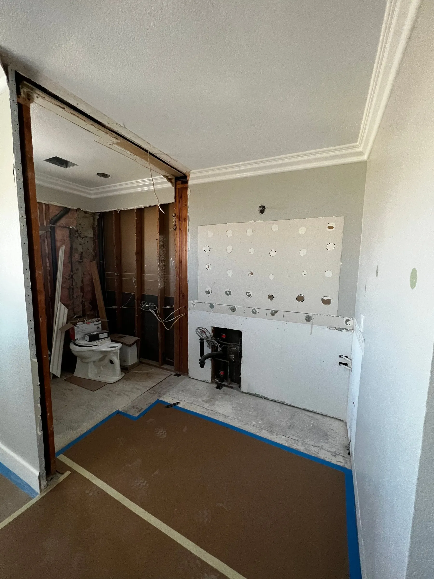 Bathroom remodel during demolition, walls opened to the studs with floor protection down