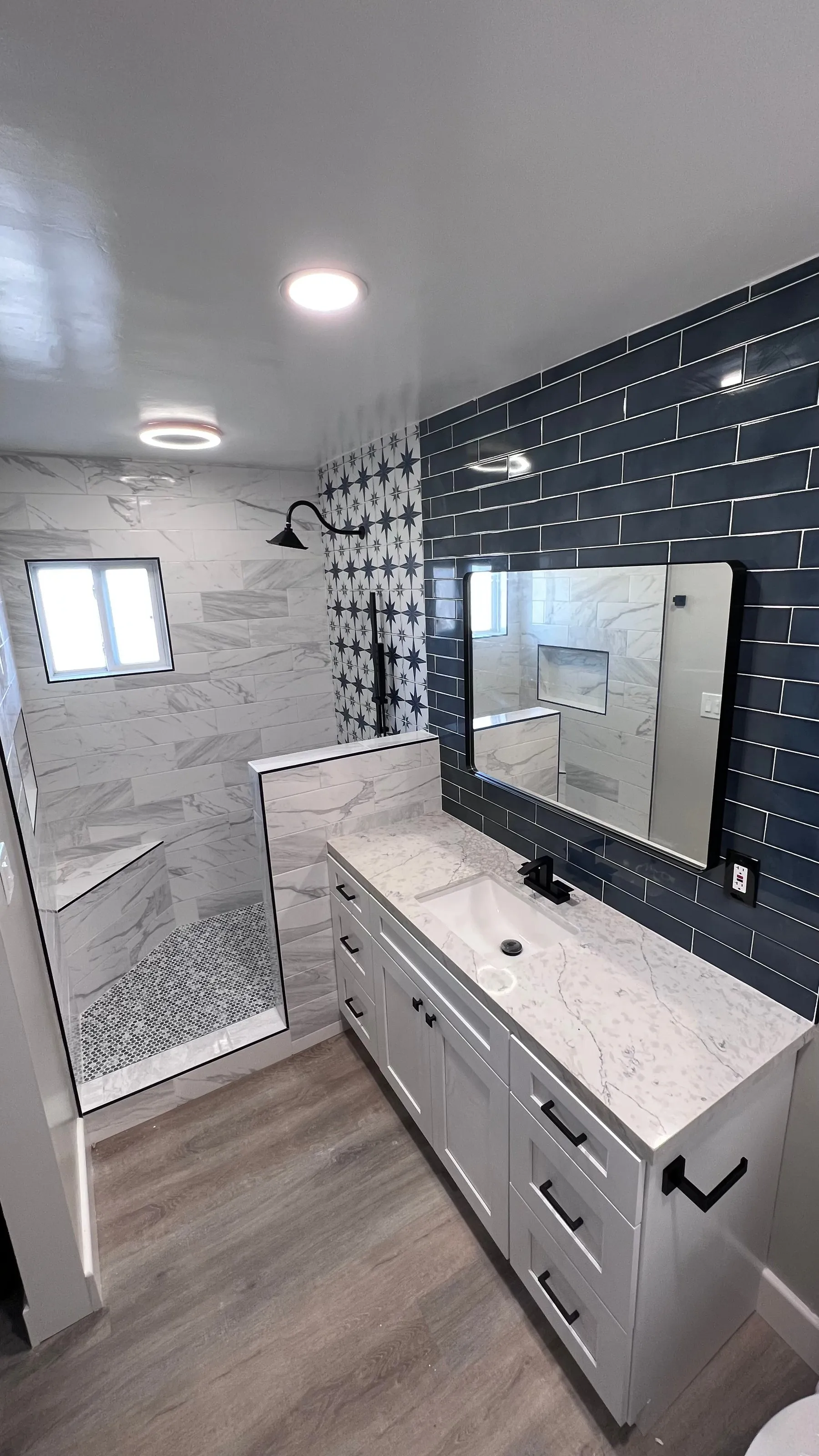 Finished bathroom remodel with navy subway tile and a walk-in shower